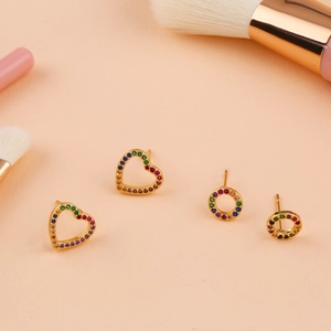 Macro detail of heart and round gold earrings with colorful cubic zirconia stones