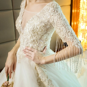 Elegant ivory wedding dress with gold embroidery, V-neckline, and beaded tassel sleeves