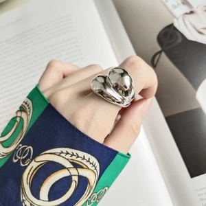 Polished chunky silver ring on finger with vintage cuff and magazine background