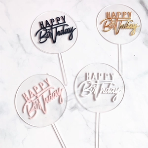 Macro view of four colorful acrylic Happy Birthday round cake toppers on marble background