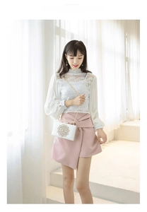 Detail of white evening clutch featuring a large crystal floral motif and gold chain strap