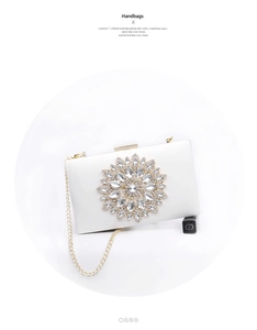 Detailed view of white satin evening clutch with large crystal flower and gold chain strap