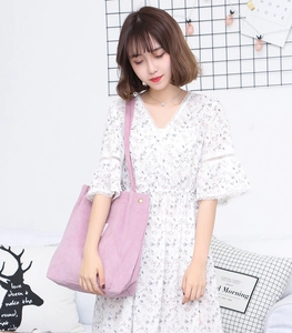 Detailed view of purple corduroy tote bag worn by model in a cozy minimalist home setting