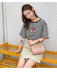 Detail of pink crossbody bag with cat-ear golden metal handle and chain strap on a model