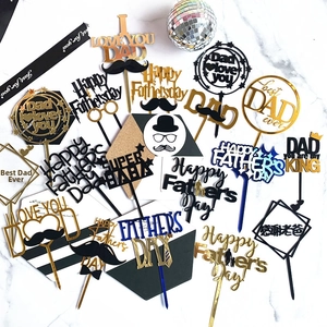 Flat lay of multiple acrylic Father's Day cake toppers in gold and blue on marble background