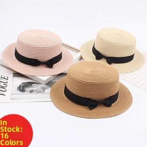 Detailed view of woven straw sun hats in pink, beige, and brown with black ribbons
