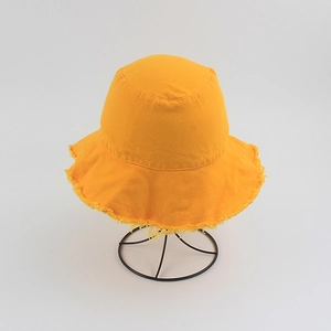 Detailed view of yellow canvas bucket hat featuring frayed edges on a metal stand
