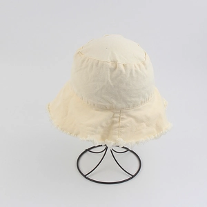 Detail view of frayed edges on a minimalist cream-colored cotton bucket sun hat