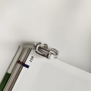 Close-up of a triple-layered silver ring featuring micro-pave cubic zirconia and unique bridge clasp