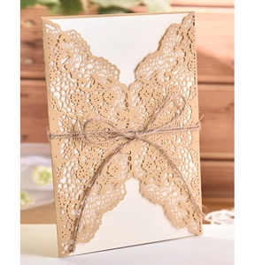 Macro shot of laser-cut butterfly invitation with kraft paper casing and twine bow detail