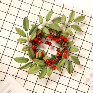 Couronne de Noël avec baies rouges et pommes de pin sur un support à carreaux