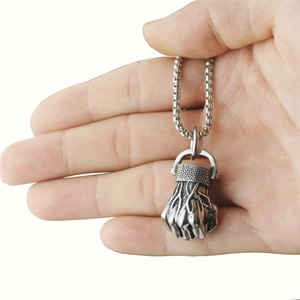 Polished silver fist pendant necklace for men being held against a white background