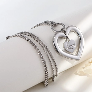Silver hollow heart LOVE necklace with Cuban chain on elegant white jewelry stand