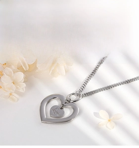 Close-up of double heart pendant necklace with Love engraving and silver finish chain
