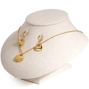 Golden heart jewelry set with necklace and pearl accent earrings on linen bust display