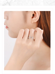 Close-up of silver open ring with curly cloud pattern on a finger with marble background