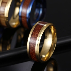 Gros plan d'une large bague en titane et acier avec métal doré et incrustation de teck