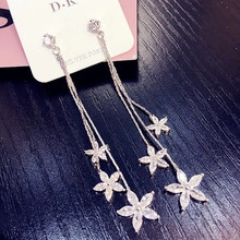 Detail of silver long tassel earrings with sparkling rhinestone flowers and silver post