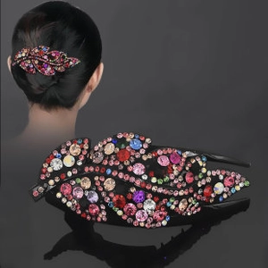 Detail of leaf-shaped hair clip with colorful rhinestones on a black metal base