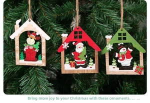 Detail of laser-cut wooden Christmas pendants with elk and Santa hanging on a pine tree