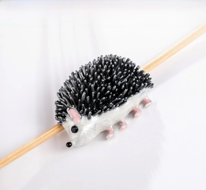 Detail of cartoon hedgehog brooch with white enamel body and black crystal eyes