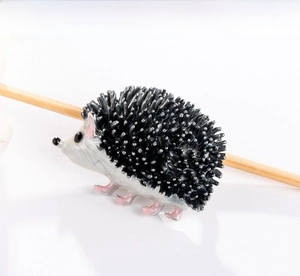 Detail of cartoon hedgehog enamel brooch showing black spikes and vintage silver finish