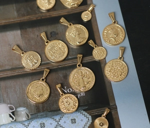 Detail von antiken 18K vergoldeten Titanstahl-Römermünzen-Anhängern auf einer Holzfläche