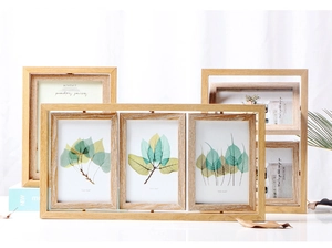 Detail of Nordic wooden photo frames with natural wood grain and botanical leaf prints