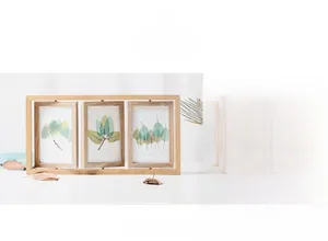 Close-up of triple rotating natural wood photo frames with decorative green leaf inserts