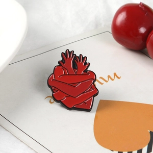 Vue détaillée de la broche en émail rouge en forme de cœur sur un fond de carte décoratif