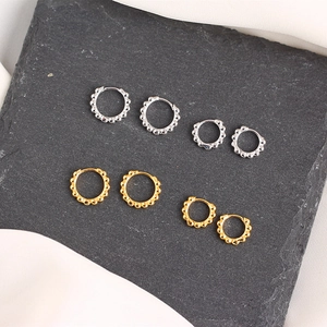 Flat lay of gold and silver bead-edged hoop earrings in various sizes on slate