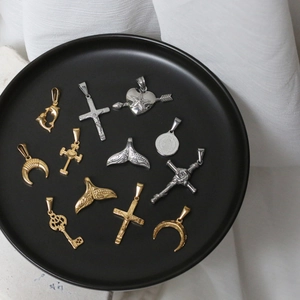 Macro detail of vintage coin, mermaid tail and crescent steel pendants on a black plate