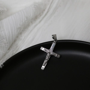 Macro shot of silver stainless steel crucifix pendant on black plate with detailed relief