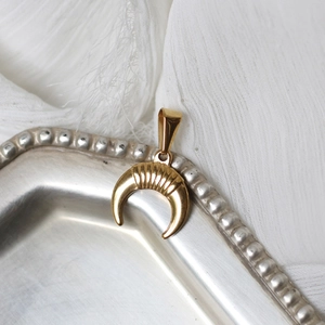 Detail of 18K gold-plated crescent moon pendant on vintage silver tray with white fabric