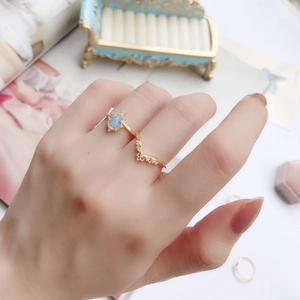 Primo piano di anelli a corona in argento 925 dorato con pietra blu e opale su mano