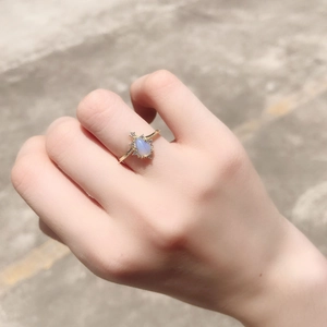 Dettaglio dell'anello dorato con opale a goccia e design in pizzo sulla mano