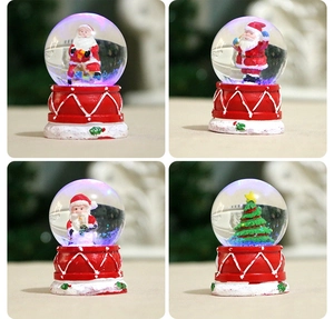 Macro view of four light-up Christmas snow globes with red bases and glowing LED scenes