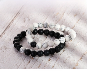 Close-up of black matte agate and white turquoise beaded bracelets on wood background