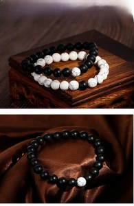 Detail of beaded elastic bracelets with matte black agate and white marble stones