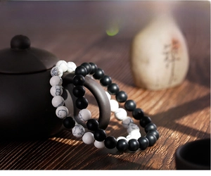 Detailed view of matte black agate and white turquoise beaded bracelets on a teapot handle