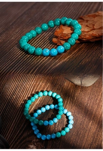 Detailed view of turquoise bead bracelet with natural black veining on rustic wood