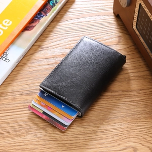 Detail of slim black leather RFID card holder with automatic pop-up slots on wooden desk