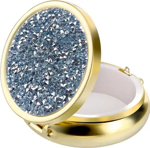 Detailed view of portable round metal pill box with light blue rhinestones and white lining