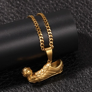 Macro shot of gold hip hop pendant featuring a detailed soccer shoe and ball on a Cuban chain