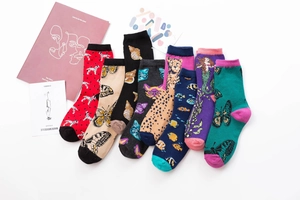 Flat lay of eight mid-calf cotton socks with assorted artistic animal and floral prints
