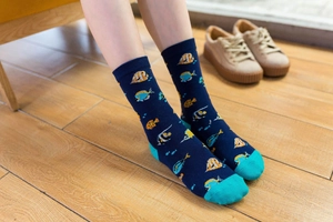 Detail of dark blue cotton crew socks featuring colorful cartoon fish patterns and teal accents