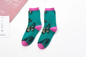 Detailed view of green cotton crew socks with pink trim and butterfly patterns