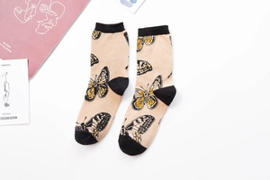 Close-up of beige crew socks with black and yellow butterfly patterns and cotton fabric