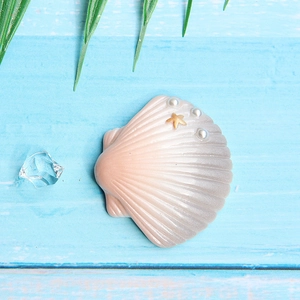 Detail of seashell resin accessory with pearls, starfish, and gold rim on blue wood