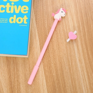 Pink unicorn gel pen with cartoon 3D figure on a wooden desk with a blue book